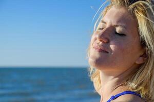 il ragazza rilassa di il mare sotto il respiro di il mare brezza. felicità di il mare. rilassante emozioni. foto