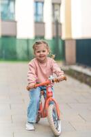 poco ragazza equitazione equilibrio bicicletta nel il cortile di il residenza nel praga, Europa foto