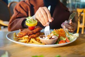 donne mangiare pollo cotoletta servito con Patata patatine fritte foto