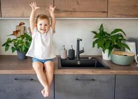 un' bambino ragazza con un' fiore su il cucina tavolo avendo divertimento foto