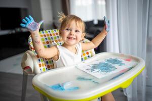 carino poco ragazza pittura con dita a casa. creativo Giochi per bambini. restare a casa divertimento foto