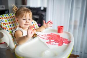 carino poco ragazza pittura con dita a casa. creativo Giochi per bambini. restare a casa divertimento foto