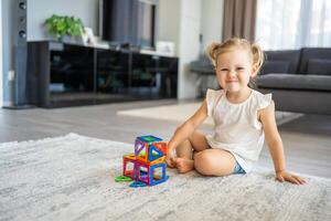 poco ragazza giocando colorato magnete plastica blocchi kit a casa. il bambino giocando educativo Giochi. presto infanzia sviluppo. foto