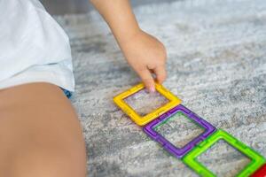 poco ragazza giocando colorato magnete plastica blocchi kit a casa. il bambino giocando educativo Giochi. presto infanzia sviluppo. foto