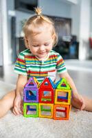 poco ragazza giocando colorato magnete plastica blocchi kit a casa. il bambino giocando educativo Giochi. presto infanzia sviluppo. foto