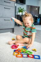 poco ragazza giocando colorato magnete plastica blocchi kit a casa. il bambino giocando educativo Giochi. presto infanzia sviluppo. foto