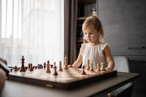 padre insegnamento il suo poco figlia per giocare scacchi a il tavolo nel casa cucina. il concetto presto infanzia sviluppo e formazione scolastica. famiglia tempo libero, comunicazione e ricreazione. foto