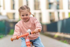 poco ragazza equitazione equilibrio bicicletta nel il cortile di il residenza nel praga, Europa foto