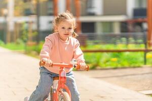 poco ragazza equitazione equilibrio bicicletta nel il cortile di il residenza nel praga, Europa foto