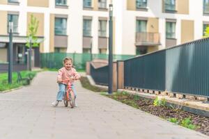 poco ragazza equitazione equilibrio bicicletta nel il cortile di il residenza nel praga, Europa foto