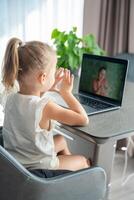 poco ragazza fa dito ginnastica in linea su il il computer portatile casa. distanza apprendimento concetto. foto
