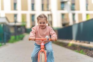 poco ragazza equitazione equilibrio bicicletta nel il cortile di il residenza nel praga, Europa foto