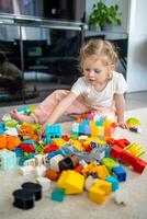 poco ragazza giocare con costruttore giocattolo su pavimento nel casa, educativo gioco, la spesa tempo libero attività tempo concetto foto