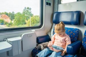 bellissimo poco ragazza utilizzando digitale tavoletta durante in viaggio di ferrovia nel Europa foto