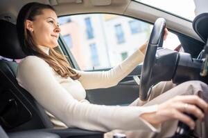 contento donna guida un' auto e sorridente. carino giovane successo contento brunetta donna è guida un' macchina. ritratto di contento femmina autista timone macchina. foto