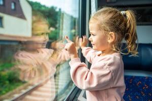 bellissimo poco ragazza guardare su treno finestra fuori, mentre esso in movimento. in viaggio di ferrovia nel ceco repubblica, Europa foto