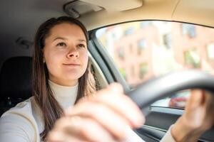 contento donna guida un' auto e sorridente. carino giovane successo contento brunetta donna è guida un' macchina. ritratto di contento femmina autista timone macchina. foto