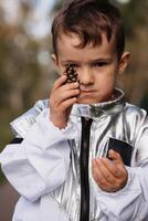 un' poco ragazzo nel un astronauta costume è giocando al di fuori su un' soleggiato giorno. verticale foto. foto