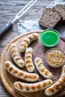 grigliato salsicce con caldo salse su il di legno tavola foto