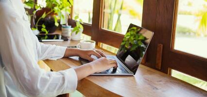 vicino su di Lavorando donna di mani utilizzando il computer portatile computer a caffè negozio. libero professionista donne chat su il Internet foto