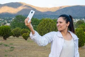 latino donna utilizzando sua cellula Telefono nel un' parco. foto