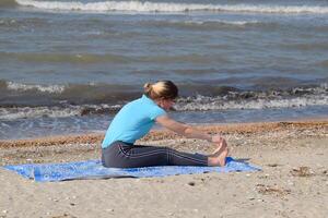 ragazza pratiche yoga di il mare. esercizio ginnastica nel il fresco aria di il mare. foto