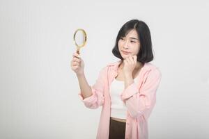 giovane asiatico donna Tenere ingrandimento bicchiere al di sopra di bianca sfondo, analisi e finanza concetto foto