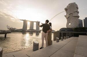 merlion Fontana nel davanti di il marina baia sabbie con giovane asiatico coppia di amore turista. foto