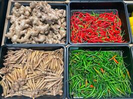 fresco biologico verdure nel cestino per vendita nel il supermercato. verde Pepe, dito radice, peperoncino, Zenzero foto