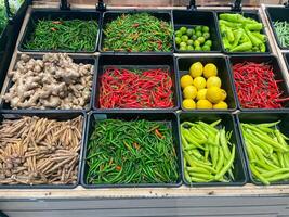 fresco biologico verdure nel cestino per vendita nel il supermercato. pomodoro, Limone, lime, verde Pepe, dito radice, peperoncino, Zenzero foto
