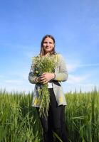 giovane bellissimo ragazza con un' mazzo di camomilla. un' donna nel un' orzo campo foto