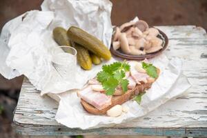 lardo con nero pane, sottaceto cetriolo per un' merenda e un' bicchiere di Vodka, ancora vita su un' peeling vecchio sgabello, alto qualità foto