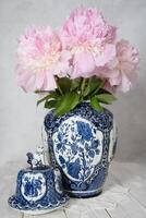 rosa lussuoso peonie nel un antico Cinese vaso con blu ornamento, primavera foto