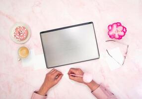 ufficio lavoratore nel un' rosa camicia si siede a un' computer portatile, superiore vista,successivo per un' tazza di caffè foto