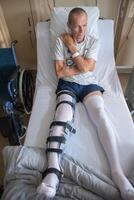un' uomo con un' rotto gamba nel un ortesi su un' letto nel un' clinica dopo un incidente e un' frattura di il femore foto