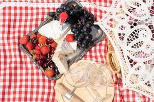 estate picnic su un' verde prato con rosso vino, formaggio e fresco frutti di bosco, uva foto