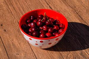 frutti di bosco di un' dolce ciliegia su un' di legno sfondo nel un' plastica tazza. maturo rosso dolce ciliegia foto