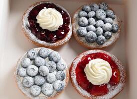 diverso pasticcini nel un' scatola, fresco torte con frutti di bosco e frustato crema, foto