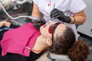 donna avendo dentale visita medica nel stomatologia clinica trattamento di carie, moderno medicinale. foto