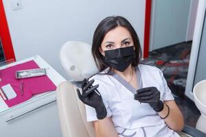 dentista l'esame paziente denti nel dentale clinica. odontoiatria e assistenza sanitaria. dentista Tenere dentale utensili nel sua mani. foto
