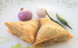 un' samosa è un' fritta Pasticcino a partire dal Sud Asia quello è pieno con salato ingredienti Compreso piselli, Maiale, pesce, cipolle, o speziato patate. anche chiamato Shingara. foto