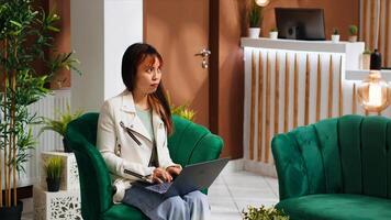 ragazza ricerca per famoso punti di riferimento per visitare durante sua vacanza, utilizzando il computer portatile nel sala la zona con gratuito Wi-Fi connessione. giovane turista pianificazione viaggio itinerario prima vedendo alloggio a Hotel. foto