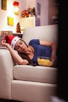 donna addormentato su divano dopo Guardando natale commedia film su televisione nel x-mas decorato cucina. ragazza godendo inverno stagione festeggiare Natale vacanza solo a casa foto