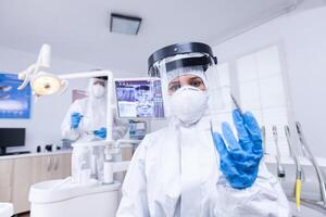 paziente pov di abile dentista nel covid protezione trattamento denti nel dentale ufficio. stomatologia indossare sicurezza Ingranaggio contro coronavirus durante heatlhcare dai un'occhiata di paziente. foto