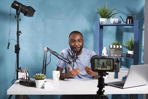 africano americano blogger la creazione di professionale video soddisfare con telecamera mentre streaming nel studio. Internet influencer emittente e A proposito di nel microfono per iscritti foto
