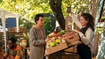 Due uomini potabile fatti in casa vino e donne assunzione fotografie, diverso persone godendo autunno giorno a Locale agricoltori mercato strada In piedi. allegro clienti e fornitori campionamento bio prodotti. foto