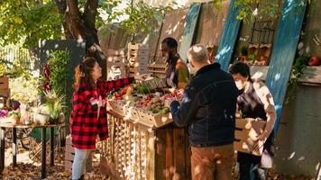 giovane contadino servendo cliente con vario produrre e vendita homegrown azienda agricola verdure a Locale cibo mercato. femmina cliente acquisto fresco biologico frutta e la verdura, agricoltura nutrizione. foto