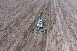 coltivazione di suolo per il semina di cereali. trattore aratri il suolo su il campo foto