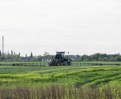 trattore con un' spray dispositivo per finemente disperso fertilizzante. foto