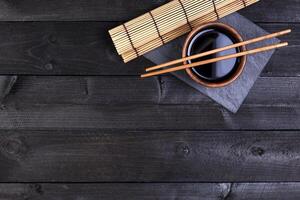 bambù stuoia, soia salsa, bastoncini su buio tavolo foto